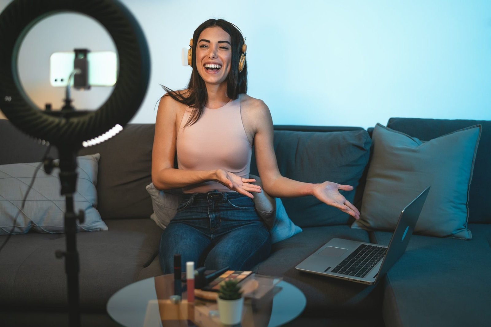 female-influencer-vlogging-online-with-smartphone-cam-and-laptop-from-home-e1651201762745